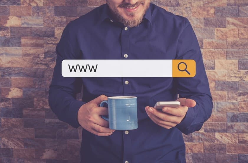A man with a coffee mug in one hand and a cell phone in the other with a search bar overlaid on top of the image, implying that he is searching for domain names.