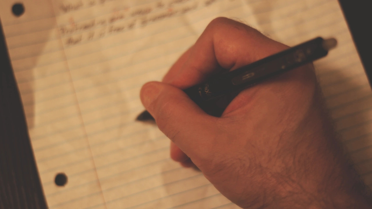 Ghostwriting on a piece of lined paper with a pen