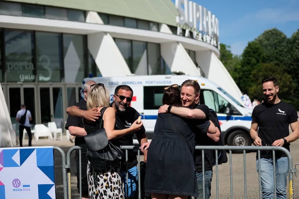 A group of WordPress contributors hugging at WordCamp Europe 2022.